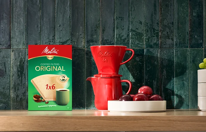 Afbeelding van een rode porseleinen koffiepot en filterhouder, vergezeld door een van onze koffiefilterdozen in het formaat 1 x 6.