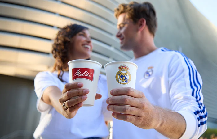 Real Madrid fans laughing at each other while holding Melitta cups