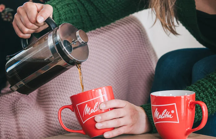 image of a lady serving a cup of coffee made with our Melitta French press