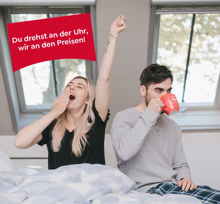 Frau & Mann sitzen im Bett. Sie gähnt, er trinkt aus einer Melitta Tasse. Text: Du drehst an der Uhr, wir an den Preisen.