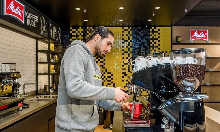 een Borussia Dortmund voetballer die een Melitta koffie bereidt