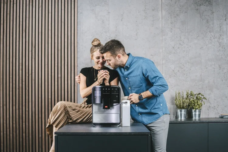 Lächelndes Paar mit einer silbernen Melitta Barista T Smart in moderner Küche