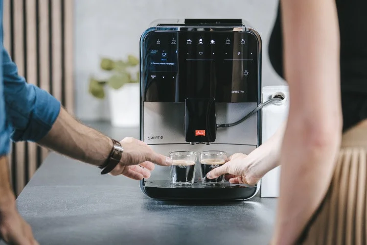 Zwei Personen nehmen frische Espressi aus einer silbernen Melitta Barista T Smart in moderner Küche