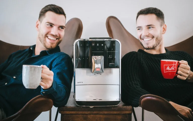 Barista Smart Vollautomat Zwei Männer genießen Kaffee mit einer silbernen Melitta CI Touch zwischen sich